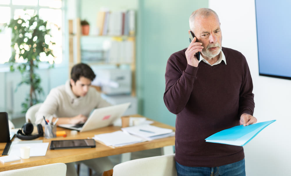 Senior man office male employee read documents and calling phone