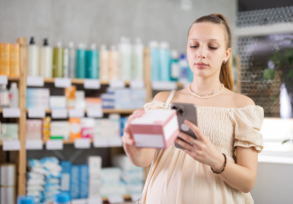 Pregnant woman in pharmacy scans QR code tablet medication product