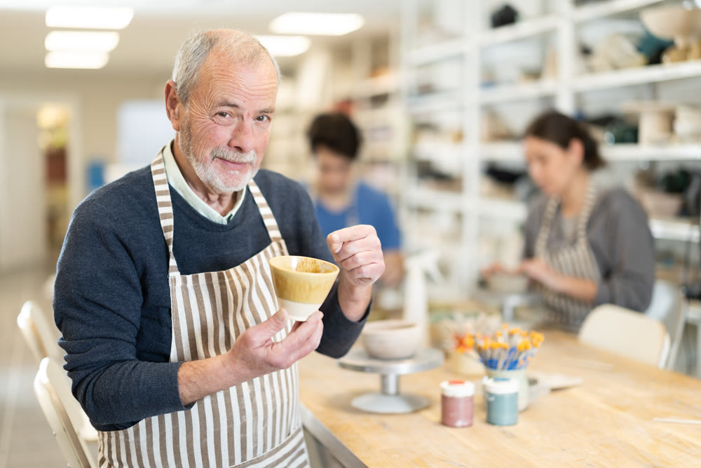 Mature potter demonstrates a clay cup he made with his own hands