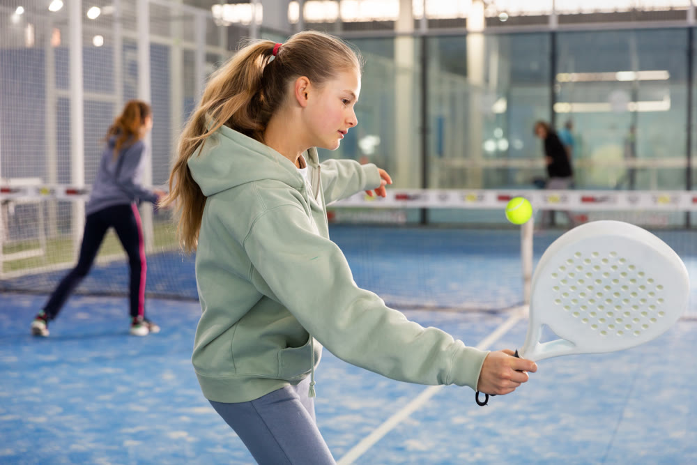 Padel game - teen girl actively kicks ball during a padel game