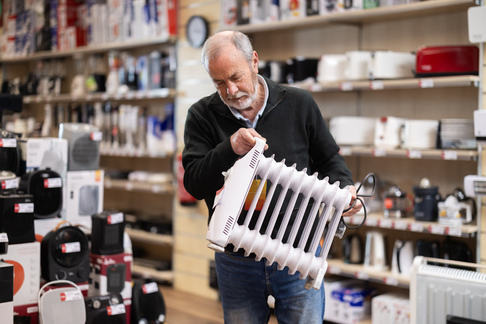 Senior man customer inspect product range and selects oil heater