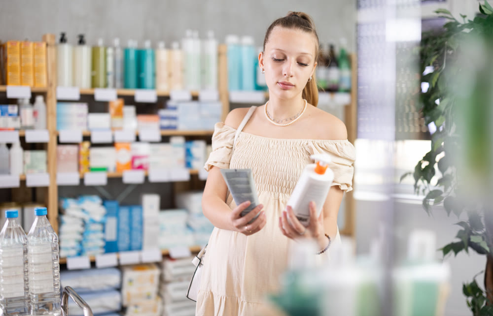 Pregnant woman are busy choosing emollient cream at pharmacy