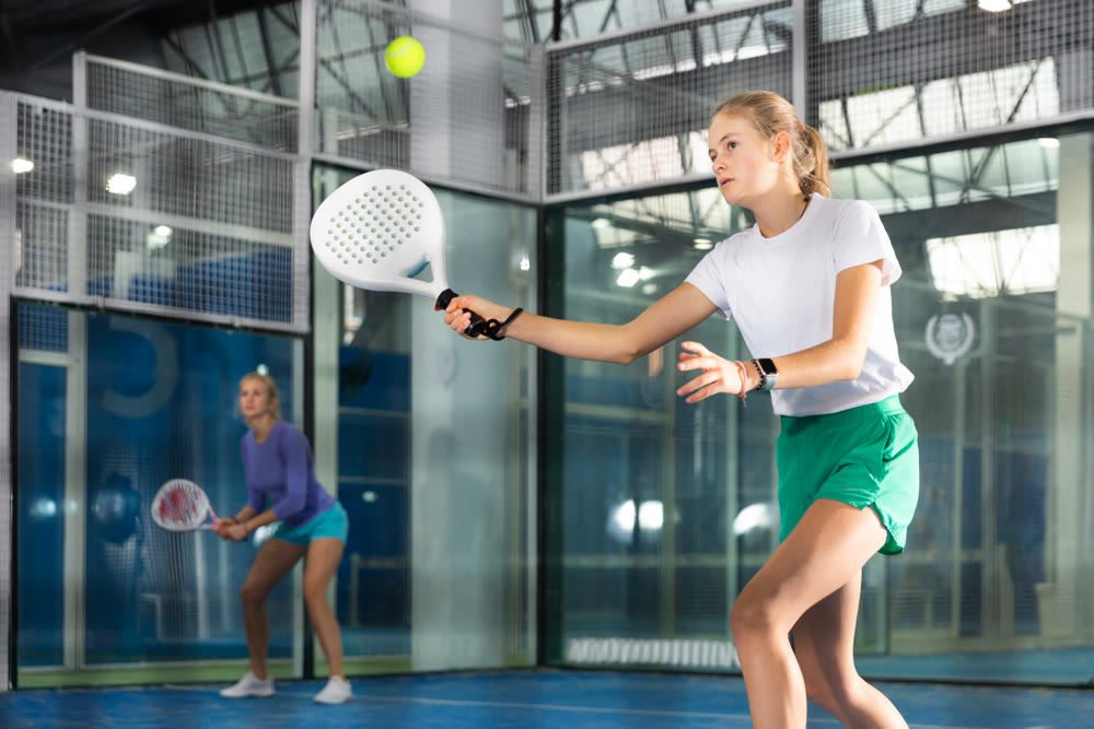 Teenage girl playing padel in court