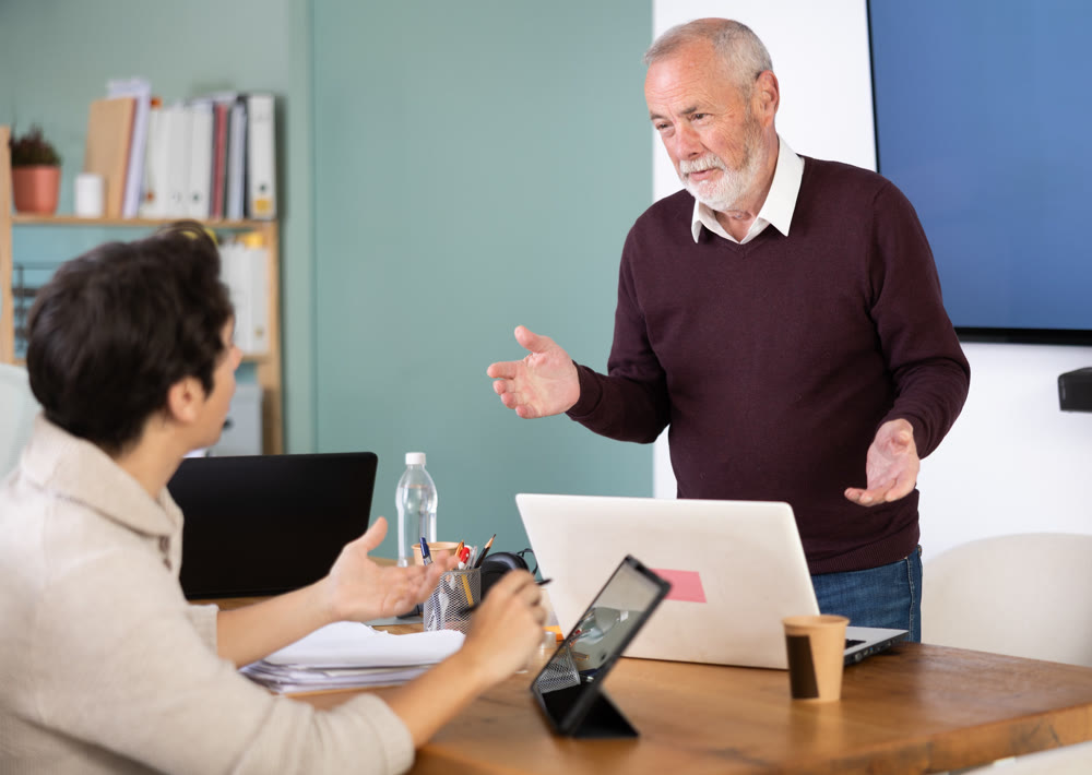 Young man working on tablet and elderly man on laptop in office