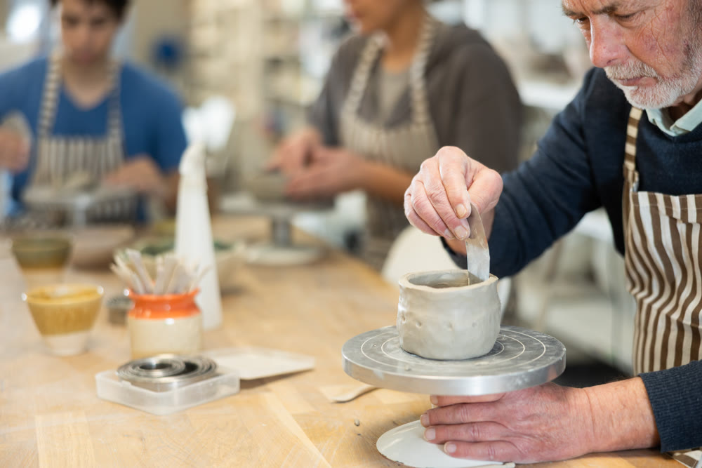 Eldery man sculpts ceramic piece in workshop