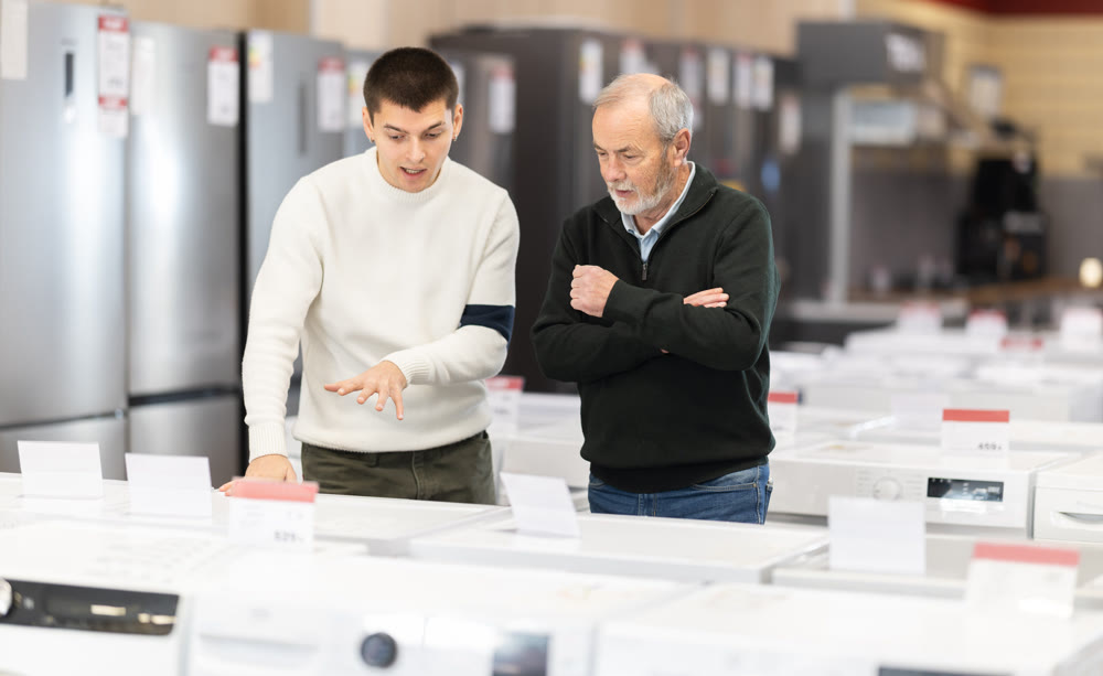 Elderly and young man choose washing machine or dishwasher