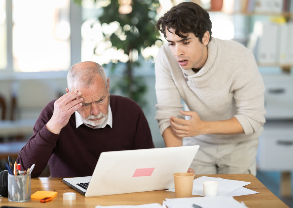 Frustrated and discouraged men in front of laptop in office workplace