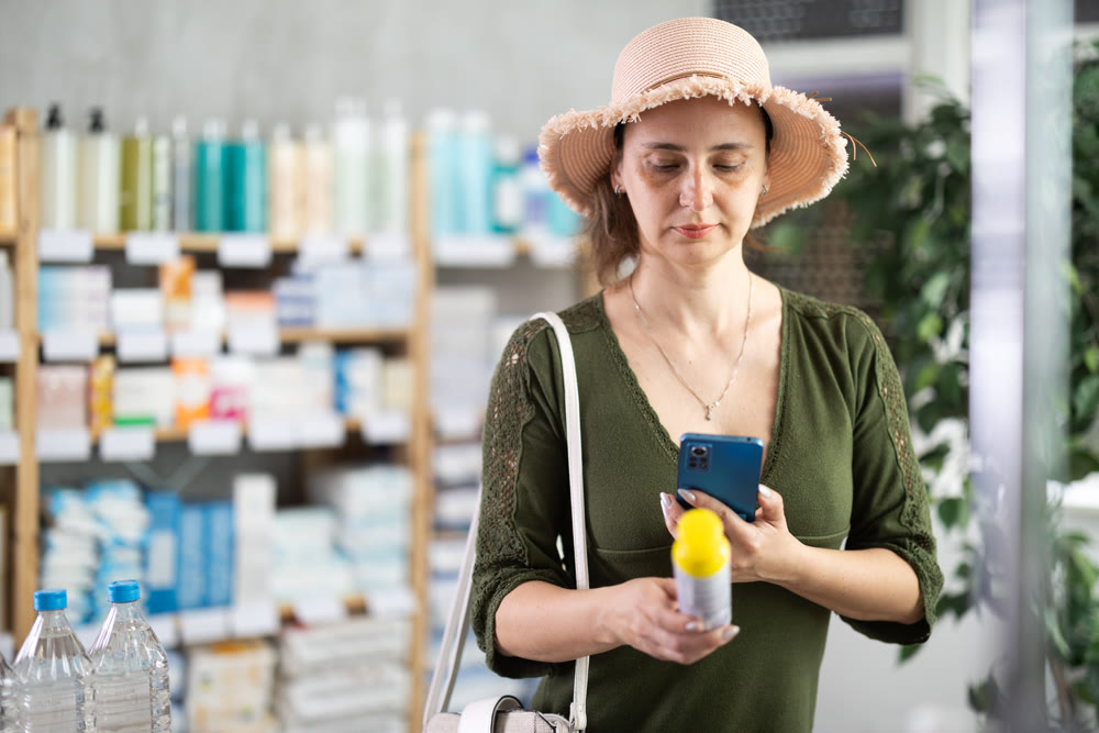 Middle-aged woman scanning barcode on repellent in chemist's shop