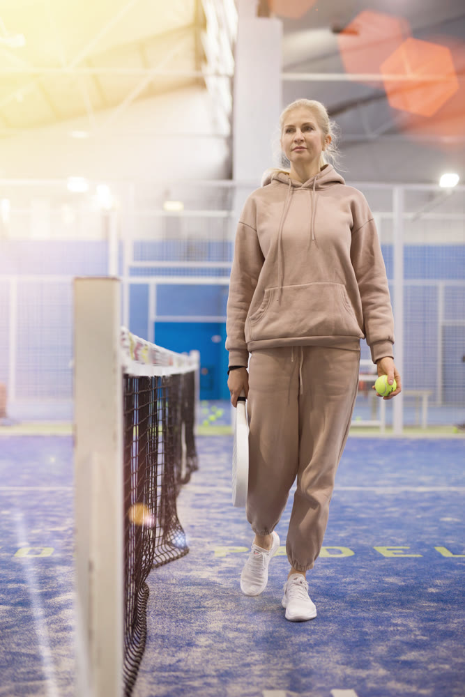 Portrait of young woman with racket and padel ball on tennis court