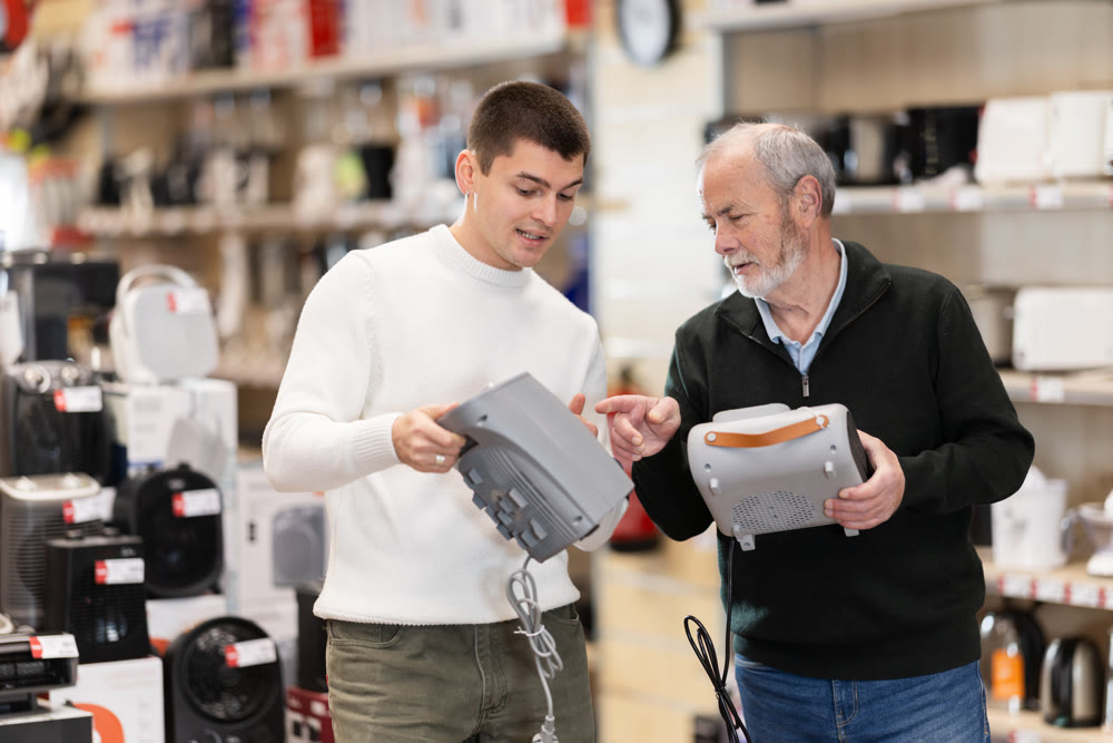 Two men choosing a household heater in an appliance store