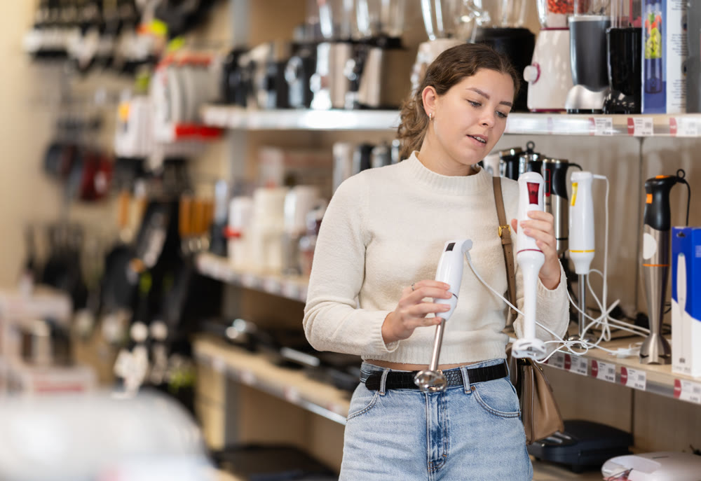 Young woman chooses blender at supermarket