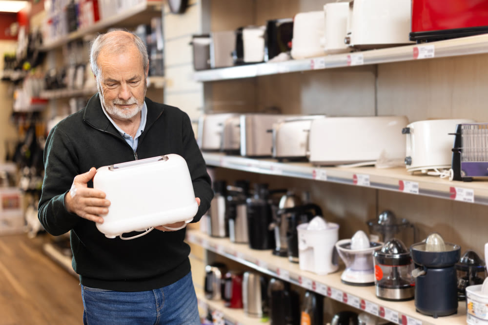 Elderly man choosing a toaster in a store