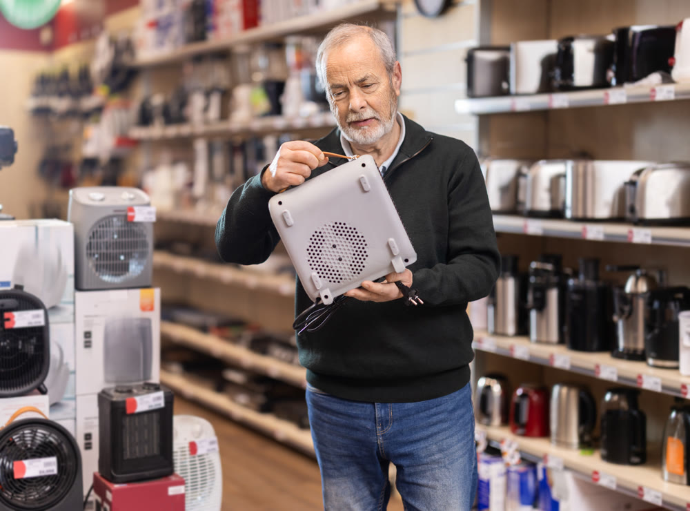 Mature man choose portable heater at supermarket