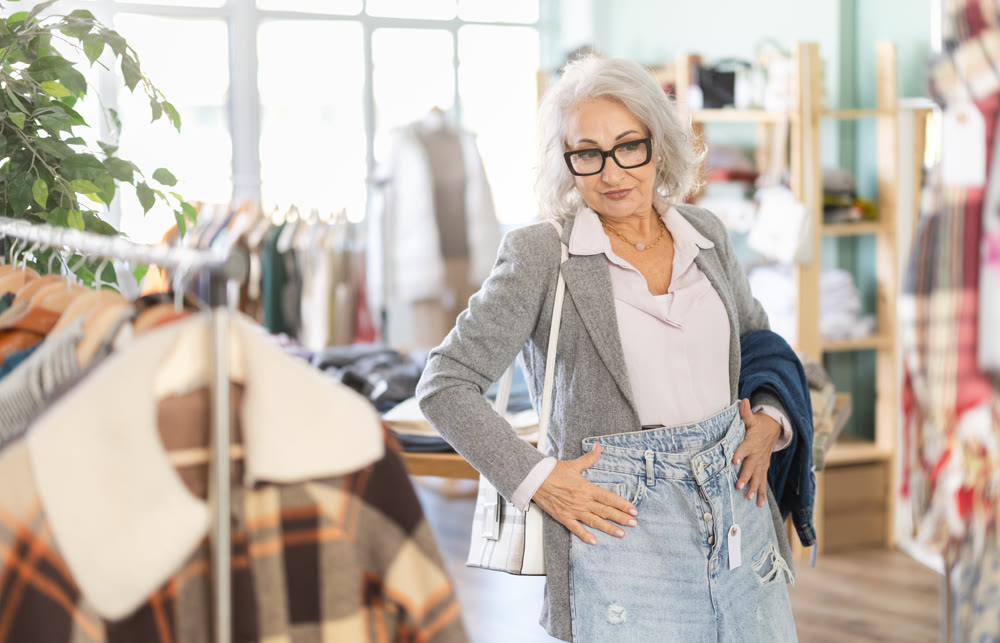 Mature woman standing in store and choosing jeans