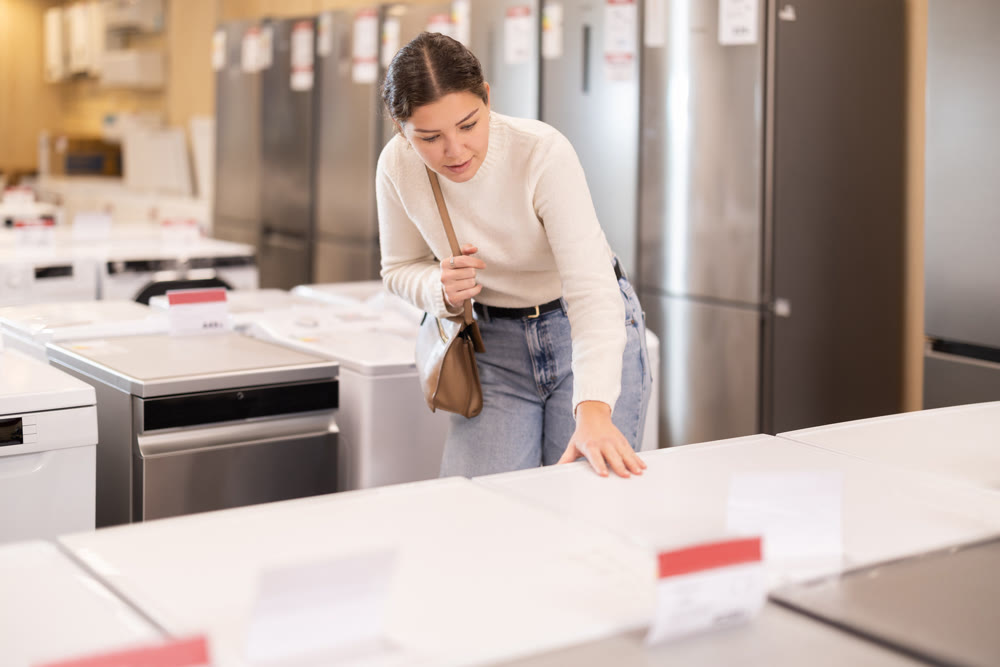 Girl customer inspect product range and selects dishwashing machine or washing machine