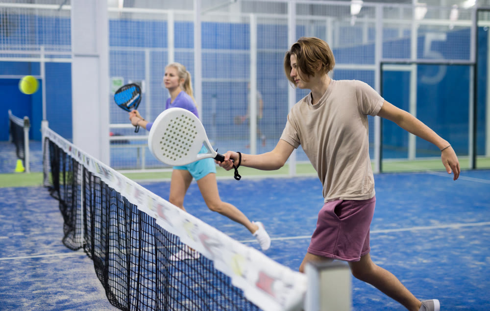 Guy playing paddle tennis on padel court indoors