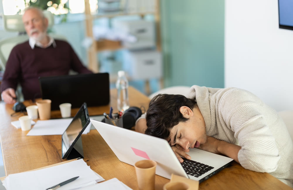 Tired male office workers having nap while sitting in workplace