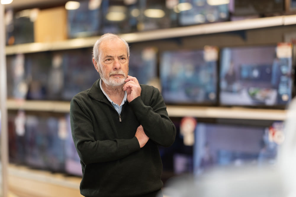 man stands near the TV sets in a store