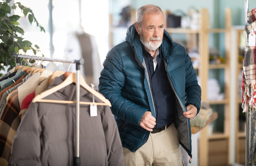 Elderly man trying on a down jacket