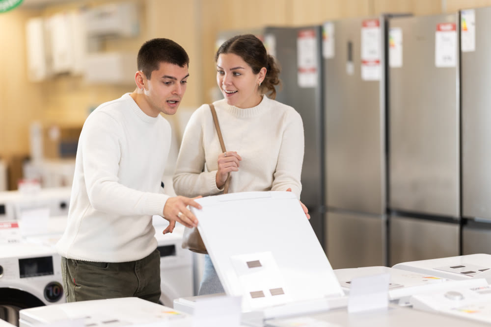 Young couple choosing washing machine or dishwasher
