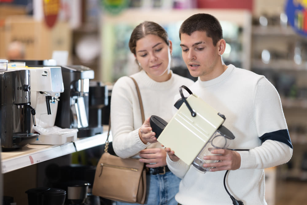 Young couple choosing coffee machine in store