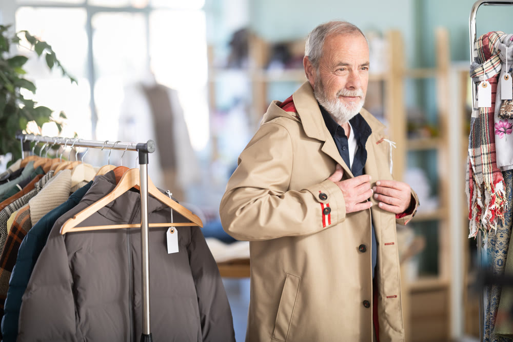 Elderly man trying on brown jacket in store