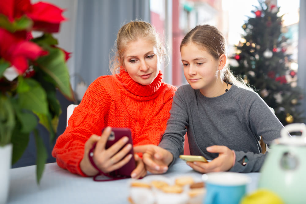 Woman and her daughter playing on smartphones