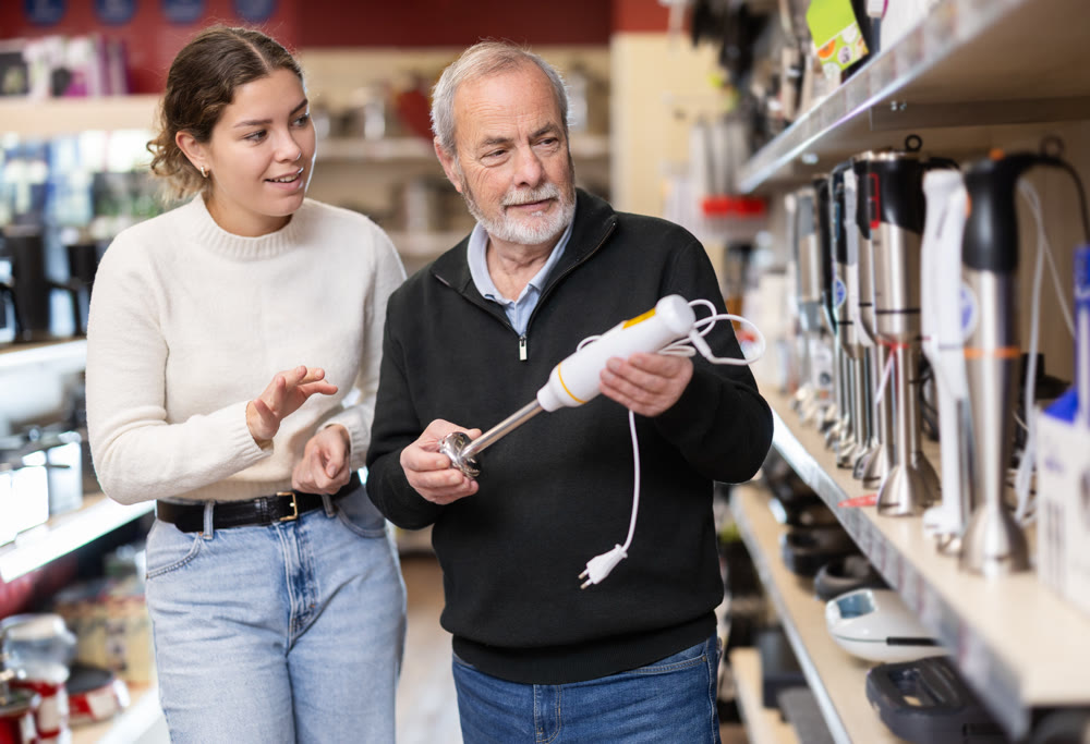 Young woman with elderly man choosing blender in store