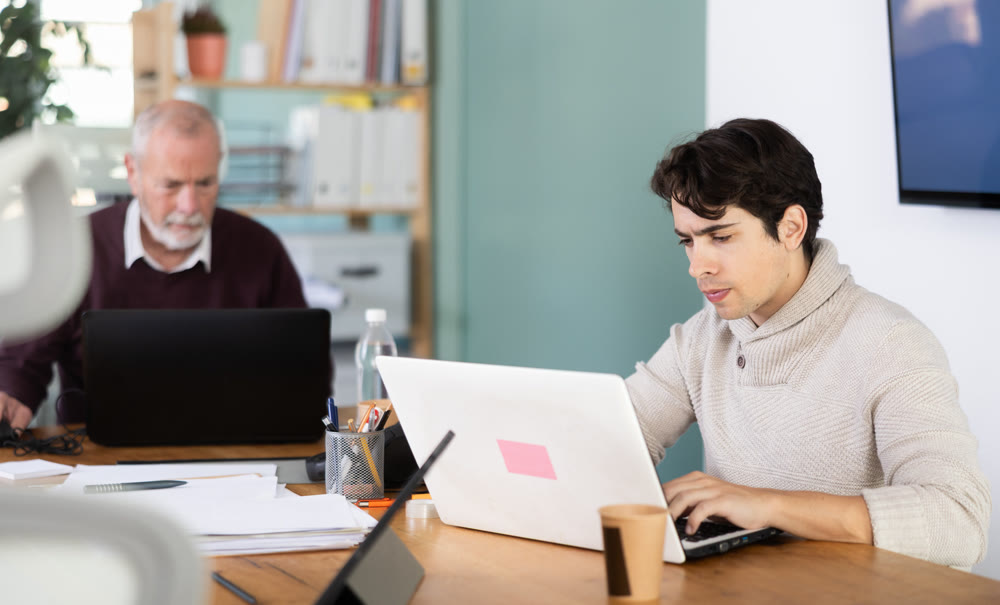 Elderly and young men working in office