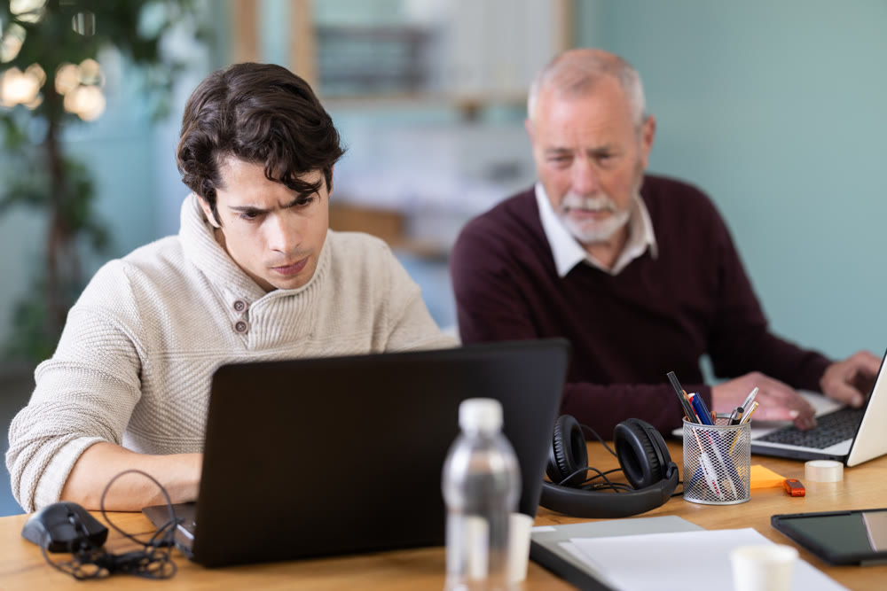 Elderly and young men working in office