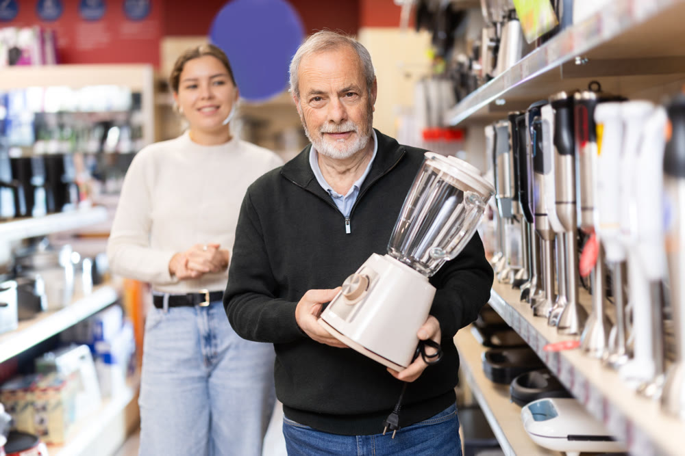 Young woman with elderly man choosing blender in store