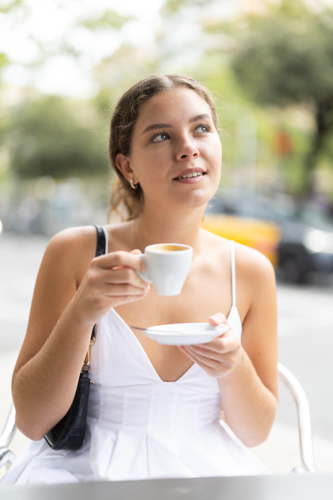 Young woman on summer terrace drinking coffee