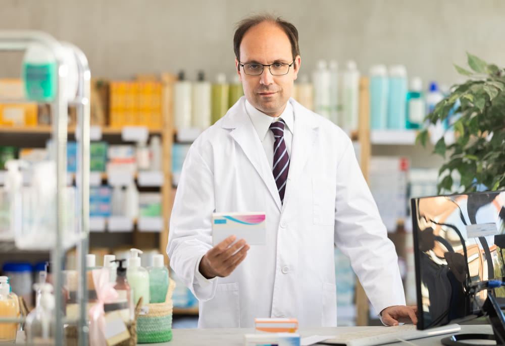 Male pharmacist offering pills in pharmacy