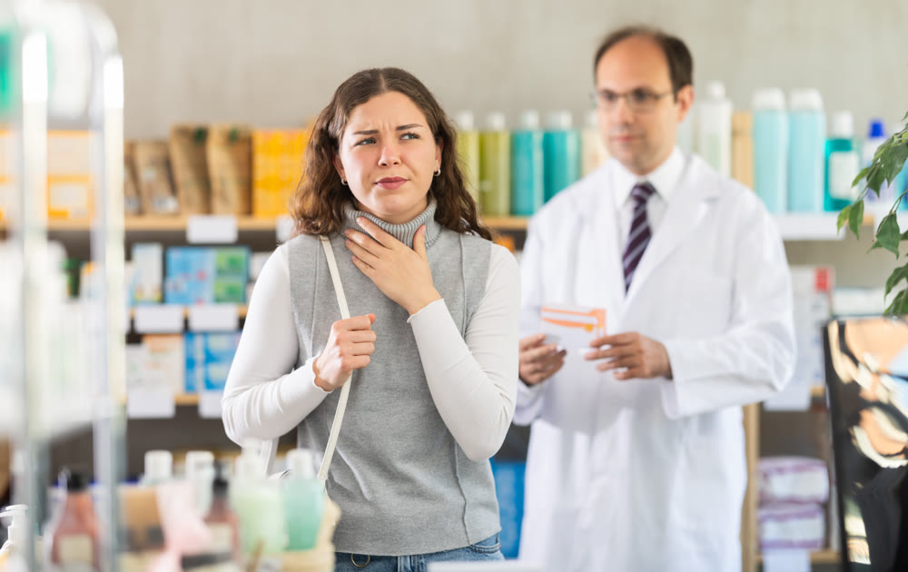 Male pharmacist offering throat pain pills to woman