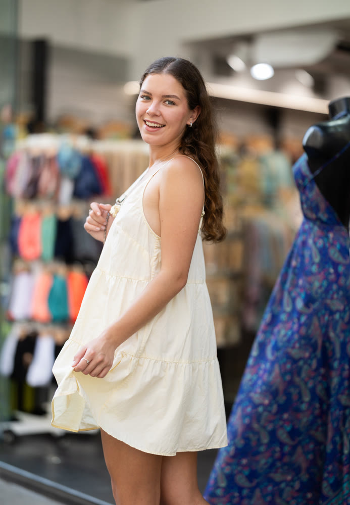 Young girl in white dress is looking for something at street market - looking at goods with interest