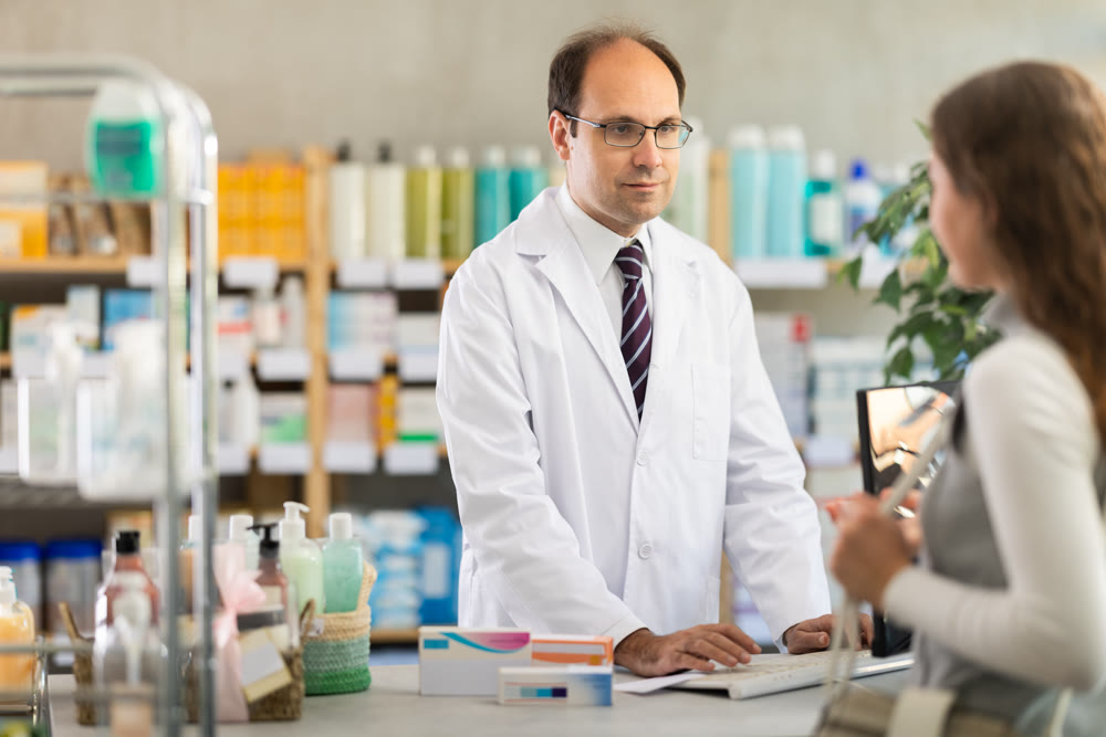 Pharmacist searches for medicine on computer for female buyer