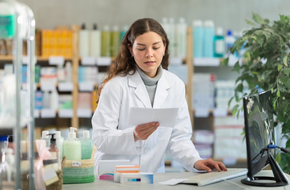 Female pharmacist checking prescription on computer