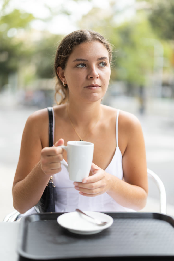 Young woman sitting in cafe and drinking tea