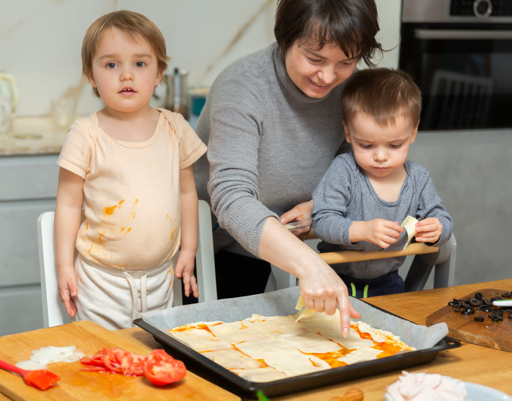 Toddler children help mom cook pizza