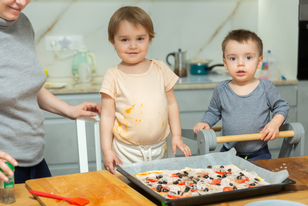 Toddler children help mom cook pizza