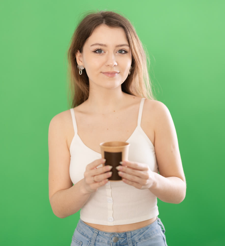 Chroma key compositing. Pretty young woman drinking coffee against green chroma key background