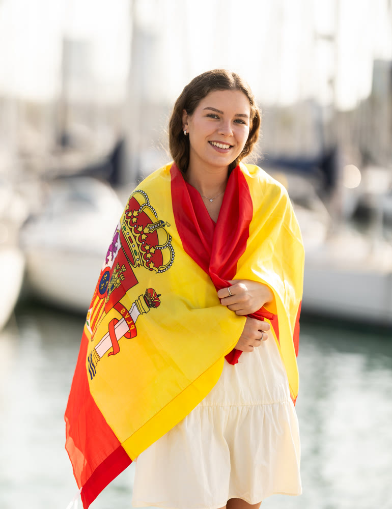 Young woman wrapped in Spanish flag in port