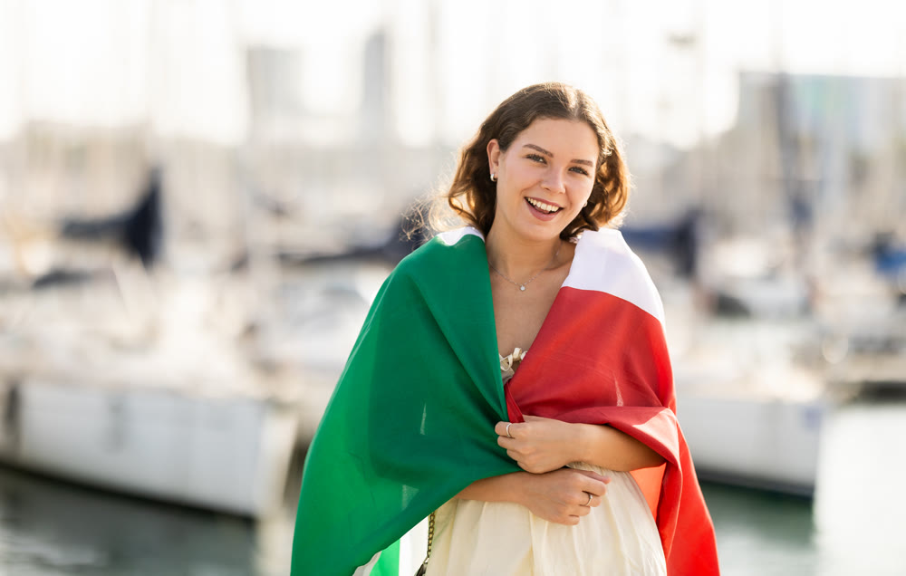 Woman waving Italian flag against seaport and yachts