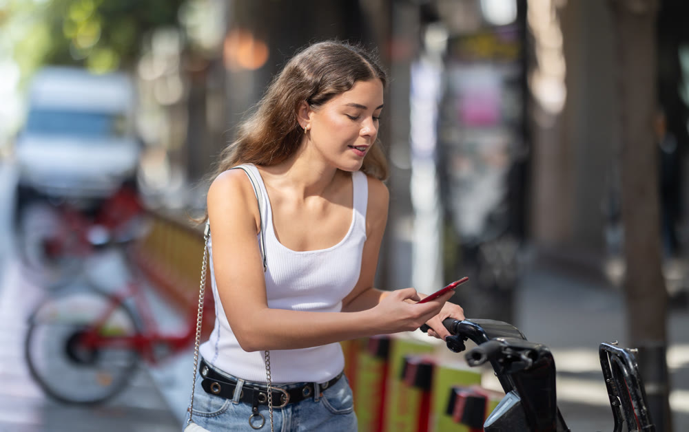 Girl rents electric bike - pays with smartphone at street parking