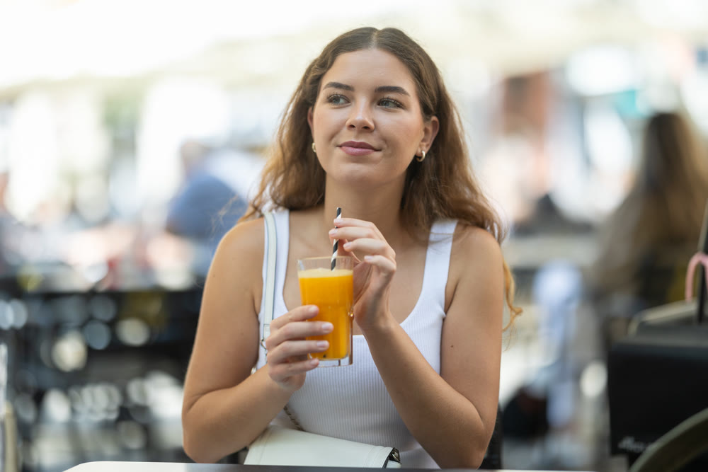 Young woman enjoying fresh juice on summer walk