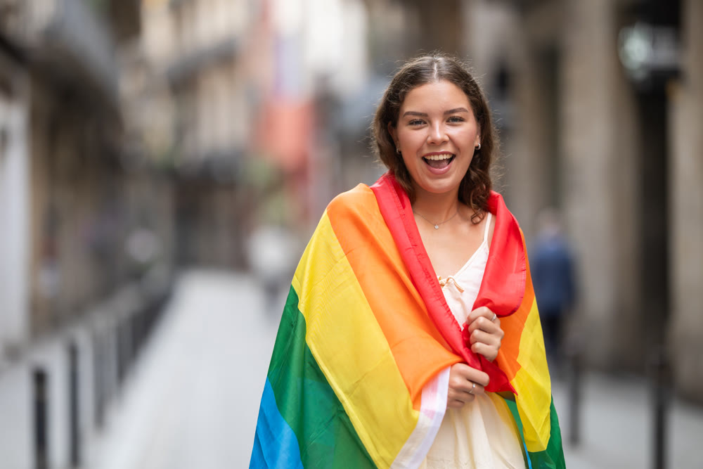 Woman waving LGBT flag on street of summer city