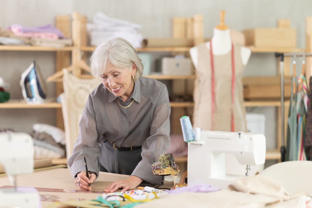 Woman dressmaker drawing pattern on paper in workshop