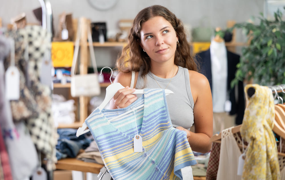 Young woman choosing vest in clothing store