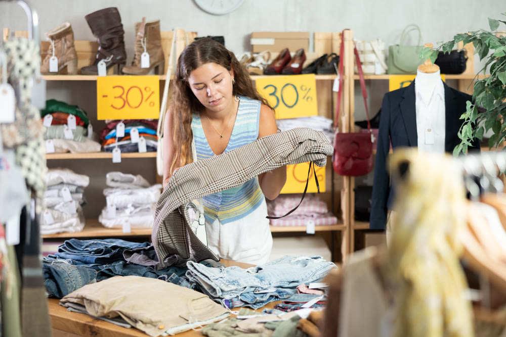 Young woman choosing trousers in clothing store