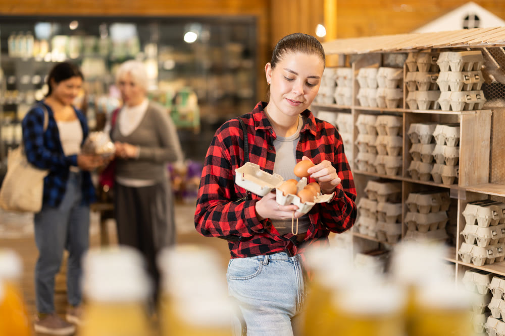 Girl selects and buys chicken eggs at grocery supermarket.